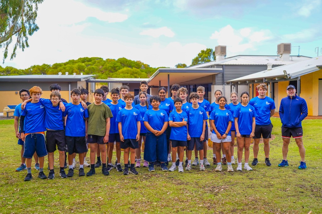 Young judoka and a coach in blue Judo WA shirts standing together on the grass at the WA Futures Camp.